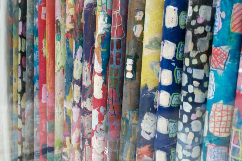 A rack of hand painted paper rolls stacked colour against colour, ready to cut