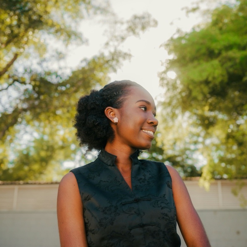 A customer looks off camera and smiles, trees soft behind her in afternoon light